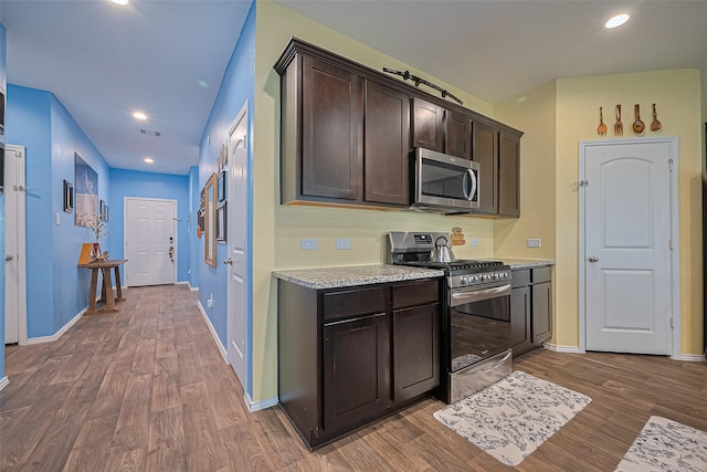 22618 Cremona Village Trl, Katy, TX 77449 - kitchen with stainless steel appliances, dark brown cabinetry, wood finished floors, recessed lighting, and light stone counters