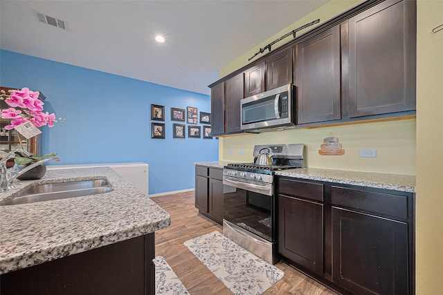 22618 Cremona Village Trl, Katy, TX 77449 - kitchen featuring appliances with stainless steel finishes, dark brown cabinetry, light wood-style floors, and recessed lighting