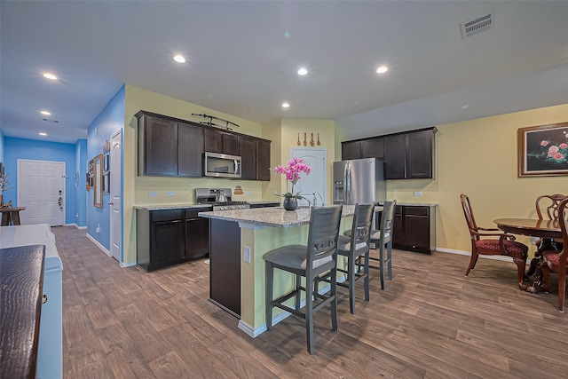 22618 Cremona Village Trl, Katy, TX 77449 - kitchen with stainless steel microwave, wood finished floors, stove, a kitchen bar, and recessed lighting