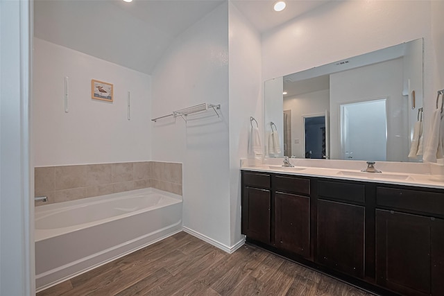22618 Cremona Village Trl, Katy, TX 77449 - bathroom featuring double vanity, a bath, wood finished floors, and vaulted ceiling