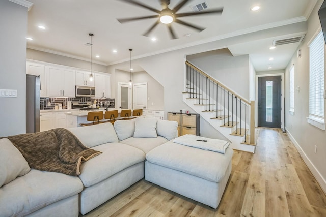 6524 Couch St, Houston, TX 77091 - living room featuring stairway, ceiling fan, light wood-type flooring, recessed lighting, and crown molding