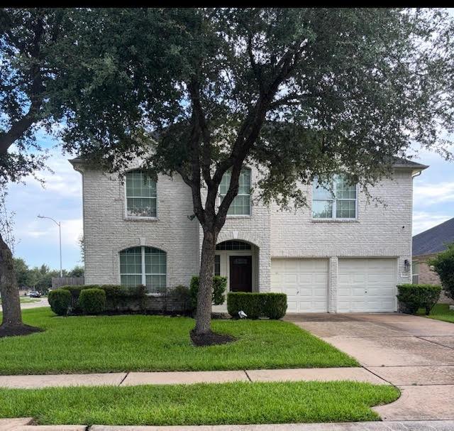 7126 Grants Hollow Ln, Richmond, TX 77407 - traditional home with an attached garage, a front yard, concrete driveway, and brick siding