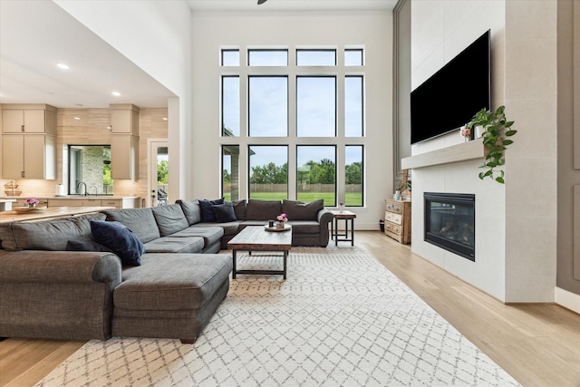 15714 Park Poetry Ct, Cypress, TX 77433 - living room featuring light wood finished floors, a tile fireplace, a high ceiling, and recessed lighting