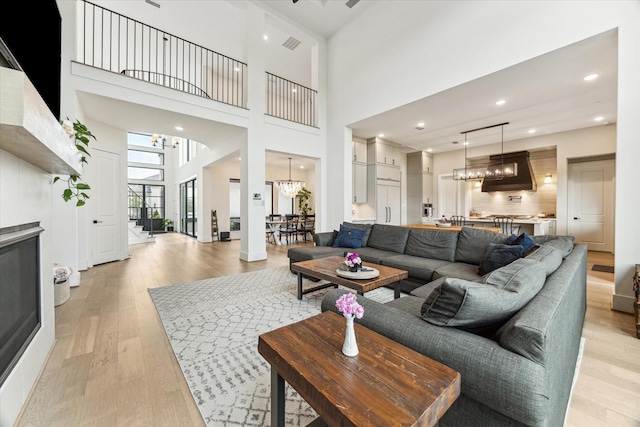 15714 Park Poetry Ct, Cypress, TX 77433 - living room with a chandelier, light wood-style flooring, a towering ceiling, and recessed lighting