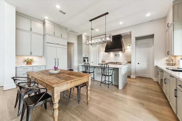 15714 Park Poetry Ct, Cypress, TX 77433 - kitchen featuring custom range hood, tasteful backsplash, a breakfast bar, recessed lighting, and light wood finished floors
