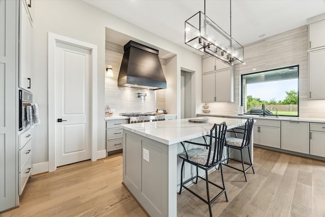 15714 Park Poetry Ct, Cypress, TX 77433 - kitchen with custom range hood, backsplash, light wood-style floors, a kitchen island, and a kitchen bar