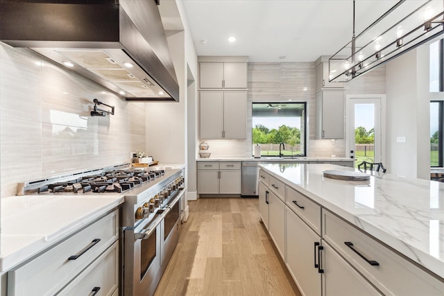 15714 Park Poetry Ct, Cypress, TX 77433 - kitchen with stainless steel appliances, wall chimney exhaust hood, tasteful backsplash, light wood-style flooring, and recessed lighting