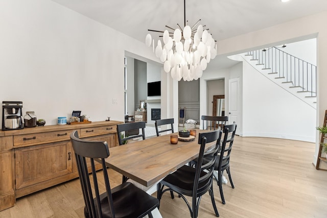15714 Park Poetry Ct, Cypress, TX 77433 - dining space with light wood-type flooring, a chandelier, stairs, and a glass covered fireplace