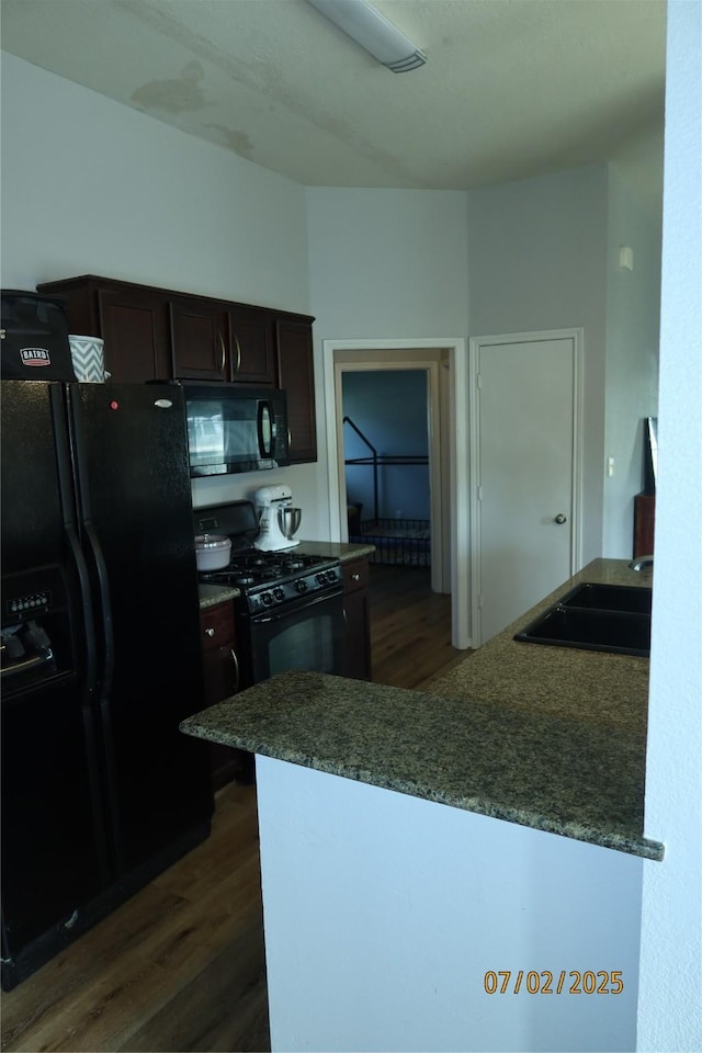 305 Duprie Dr, Brenham, TX 77833 - kitchen featuring black appliances, dark wood finished floors, dark stone counters, a peninsula, and dark brown cabinetry
