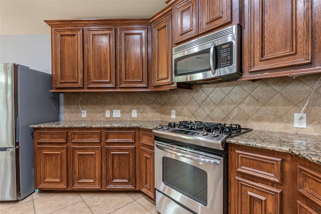 3211 Rock Brook Falls Ln, League City, TX 77573 - kitchen featuring stainless steel appliances, light stone counters, light tile patterned floors, and tasteful backsplash