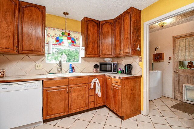 17010 Kings Walk Ln, Houston, TX 77070 - kitchen featuring white dishwasher, stainless steel microwave, washer / dryer, light countertops, and brown cabinets