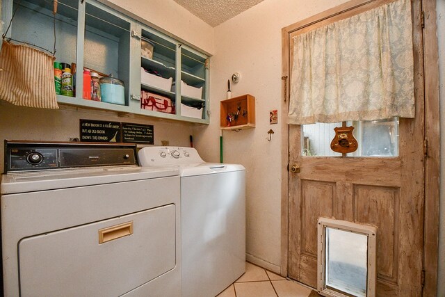 17010 Kings Walk Ln, Houston, TX 77070 - laundry room with washer and clothes dryer, light tile patterned floors, and a textured ceiling