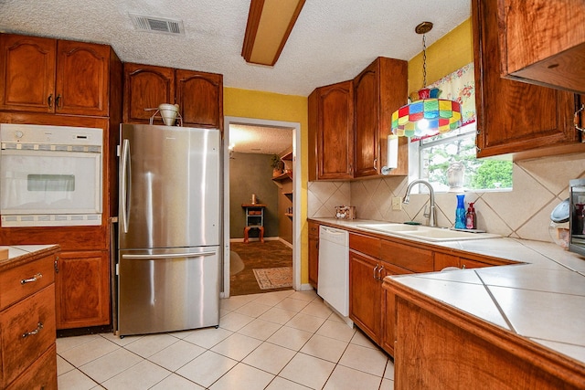 17010 Kings Walk Ln, Houston, TX 77070 - kitchen with white appliances, light tile patterned floors, a textured ceiling, backsplash, and brown cabinets