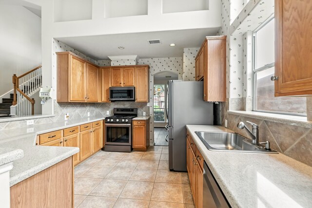 20907 Divellec Ln, Spring, TX 77388 - kitchen featuring appliances with stainless steel finishes, light countertops, backsplash, and light tile patterned flooring