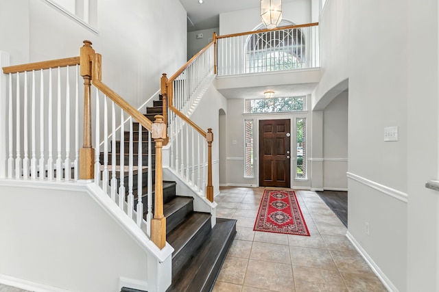 20907 Divellec Ln, Spring, TX 77388 - foyer featuring arched walkways, tile patterned floors, stairs, a towering ceiling, and a chandelier