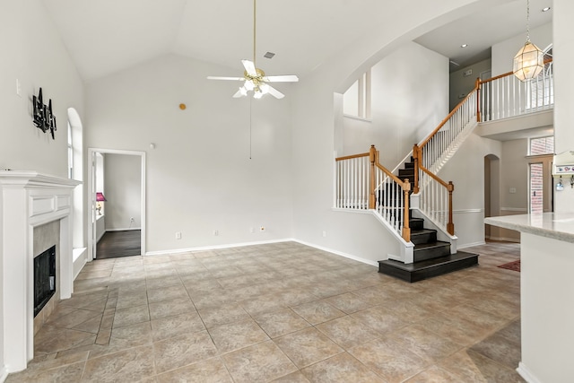 20907 Divellec Ln, Spring, TX 77388 - unfurnished living room featuring high vaulted ceiling, ceiling fan, arched walkways, stairway, and a fireplace