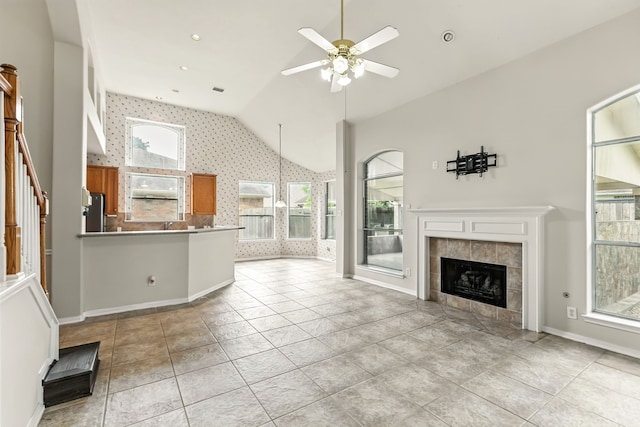 20907 Divellec Ln, Spring, TX 77388 - unfurnished living room with vaulted ceiling, healthy amount of natural light, a ceiling fan, a tile fireplace, and wallpapered walls