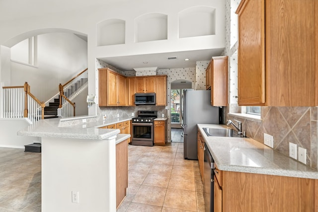 20907 Divellec Ln, Spring, TX 77388 - kitchen with stainless steel appliances, a peninsula, backsplash, light tile patterned floors, and arched walkways