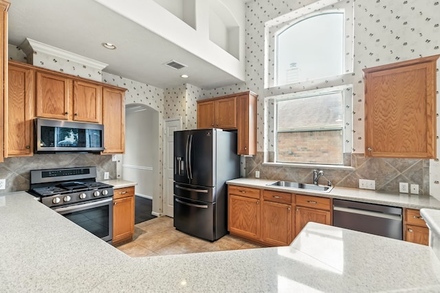 20907 Divellec Ln, Spring, TX 77388 - kitchen with appliances with stainless steel finishes, arched walkways, light countertops, light tile patterned flooring, and wallpapered walls