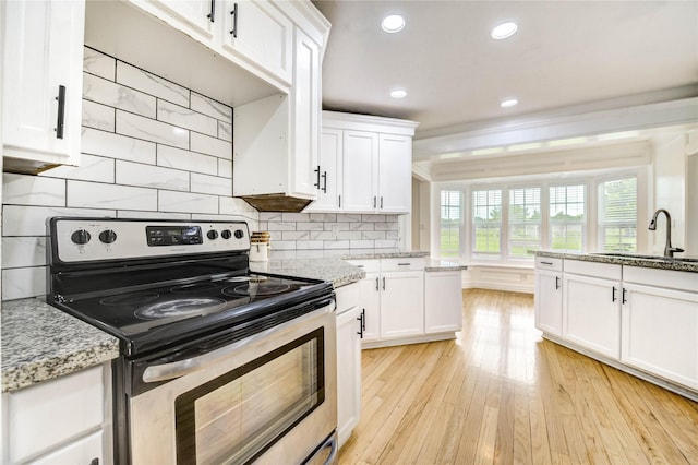 6606 Williams School Ct, Needville, TX 77461 - kitchen featuring stainless steel range with electric stovetop, white cabinetry, light wood-type flooring, recessed lighting, and light stone countertops