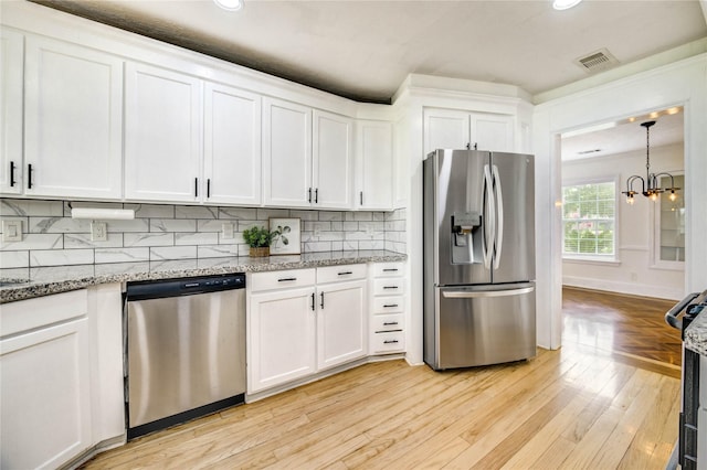 6606 Williams School Ct, Needville, TX 77461 - kitchen featuring appliances with stainless steel finishes, white cabinets, light wood finished floors, decorative backsplash, and recessed lighting