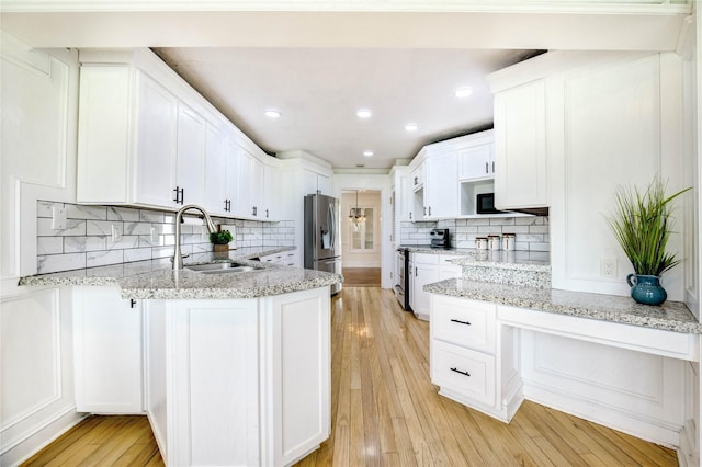 6606 Williams School Ct, Needville, TX 77461 - kitchen with appliances with stainless steel finishes, a peninsula, white cabinetry, backsplash, and light stone counters