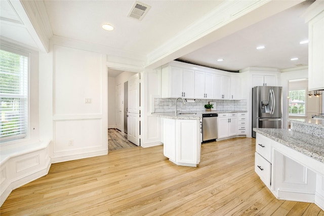 6606 Williams School Ct, Needville, TX 77461 - kitchen with stainless steel appliances, decorative backsplash, healthy amount of natural light, white cabinetry, and crown molding