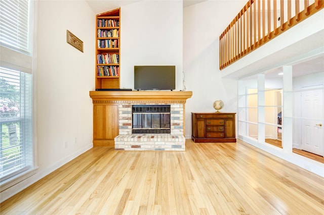6606 Williams School Ct, Needville, TX 77461 - living room featuring wood finished floors, built in shelves, a brick fireplace, and a towering ceiling