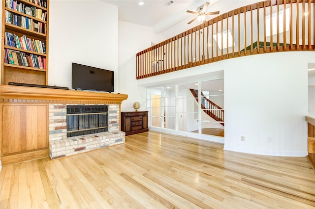 6606 Williams School Ct, Needville, TX 77461 - unfurnished living room with a fireplace, wood finished floors, a towering ceiling, a ceiling fan, and stairway