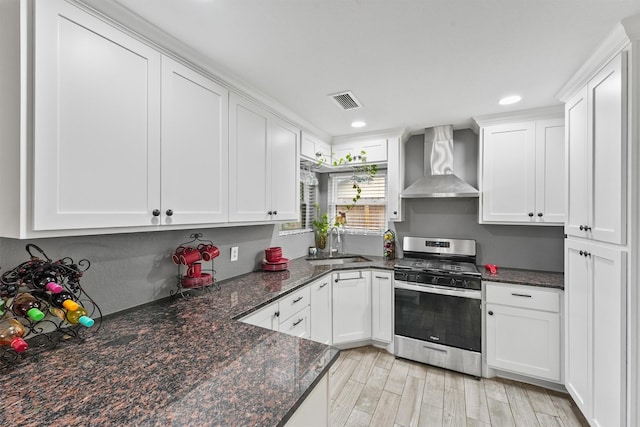 14018 Duncannon Dr, Houston, TX 77015 - kitchen featuring wall chimney range hood, stainless steel range with gas stovetop, white cabinets, recessed lighting, and dark stone countertops