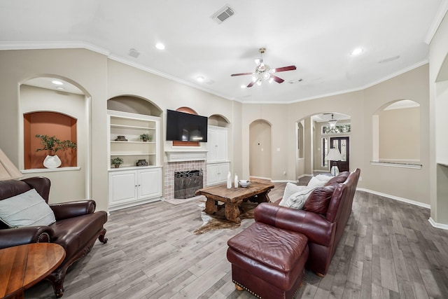 3343 Summerwood Ln, Pearland, TX 77584 - living room with a ceiling fan, wood finished floors, arched walkways, a tile fireplace, and crown molding