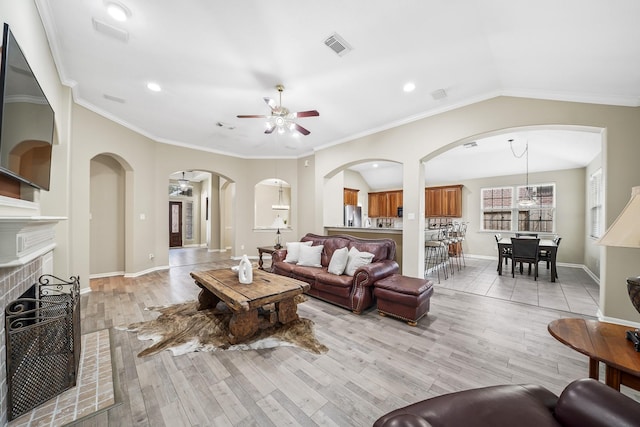 3343 Summerwood Ln, Pearland, TX 77584 - living room featuring ceiling fan, light wood-style floors, arched walkways, a fireplace, and crown molding