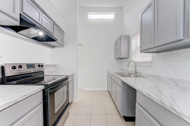 6306 Clayridge Dr, Houston, TX 77053 - kitchen featuring electric range, under cabinet range hood, gray cabinets, tasteful backsplash, and light tile patterned flooring