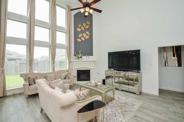 3707 Brampton Island Dr, Katy, TX 77494 - living room featuring healthy amount of natural light, a ceiling fan, a towering ceiling, wood finished floors, and a glass covered fireplace