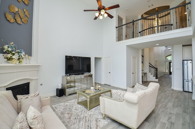 3707 Brampton Island Dr, Katy, TX 77494 - living room featuring a towering ceiling, a ceiling fan, stairway, light wood finished floors, and a glass covered fireplace