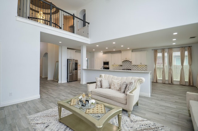 3707 Brampton Island Dr, Katy, TX 77494 - living room featuring arched walkways, a high ceiling, light wood-style flooring, and recessed lighting