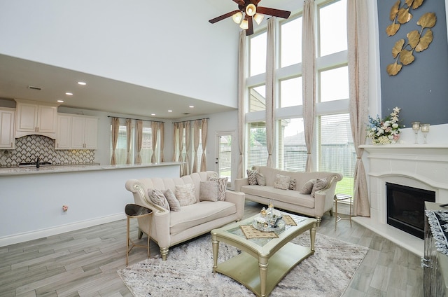 3707 Brampton Island Dr, Katy, TX 77494 - living room with a ceiling fan, light wood-type flooring, a towering ceiling, a glass covered fireplace, and recessed lighting