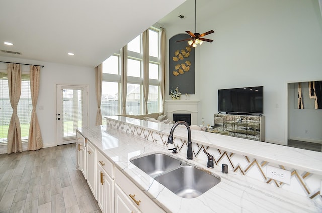 3707 Brampton Island Dr, Katy, TX 77494 - kitchen featuring open floor plan, light stone counters, a fireplace, a towering ceiling, and a ceiling fan
