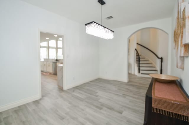 3707 Brampton Island Dr, Katy, TX 77494 - spare room featuring light wood-style floors, arched walkways, and stairs