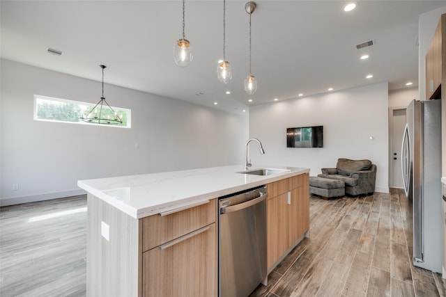 4402 Santorini Ln, Houston, TX 77045 - kitchen with stainless steel appliances, modern cabinets, open floor plan, light wood-style floors, and a center island with sink
