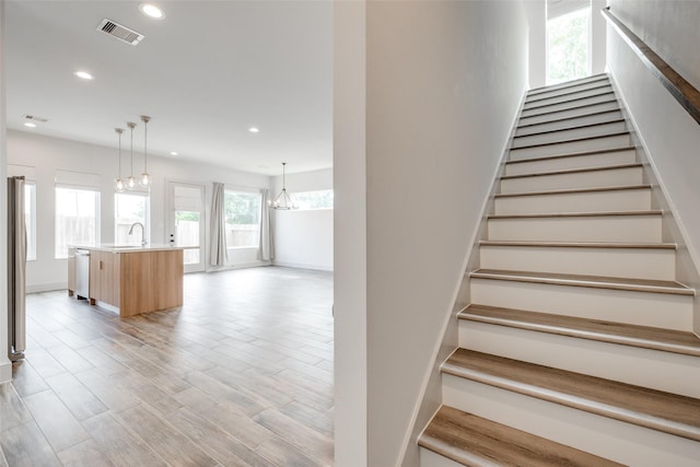 4402 Santorini Ln, Houston, TX 77045 - staircase featuring recessed lighting, wood finished floors, and a chandelier