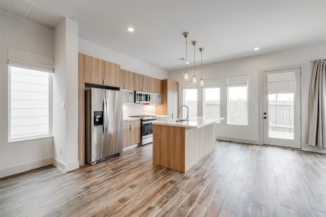 4402 Santorini Ln, Houston, TX 77045 - kitchen featuring appliances with stainless steel finishes, light countertops, modern cabinets, light wood-style flooring, and a center island with sink