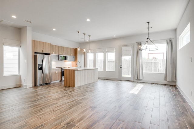 4402 Santorini Ln, Houston, TX 77045 - kitchen with stainless steel appliances, light countertops, a kitchen island with sink, light wood-style floors, and recessed lighting
