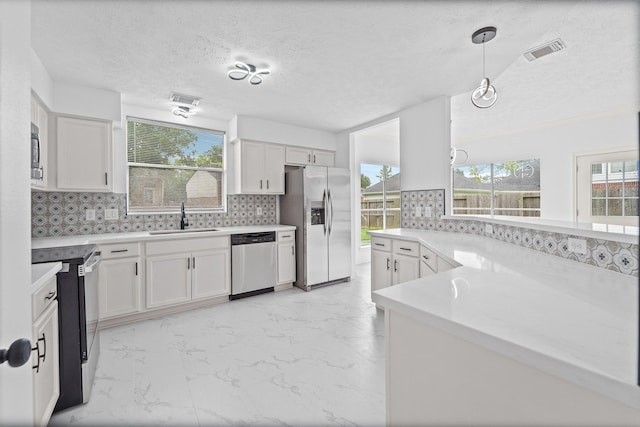 13611 Ortega Ln, Houston, TX 77083 - kitchen featuring appliances with stainless steel finishes, tasteful backsplash, white cabinetry, light countertops, and a textured ceiling