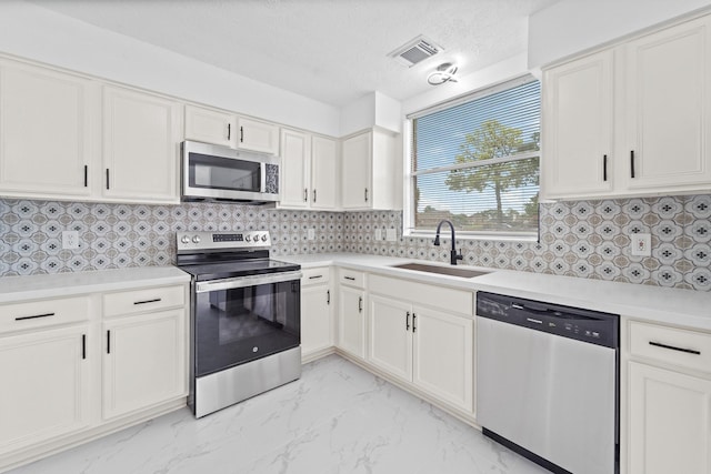 13611 Ortega Ln, Houston, TX 77083 - kitchen featuring appliances with stainless steel finishes, light marble finish flooring, white cabinetry, and light countertops