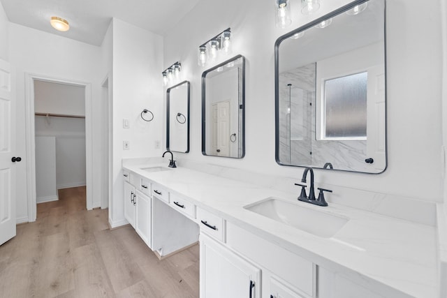 13611 Ortega Ln, Houston, TX 77083 - full bathroom featuring a marble finish shower, wood finished floors, double vanity, and a walk in closet
