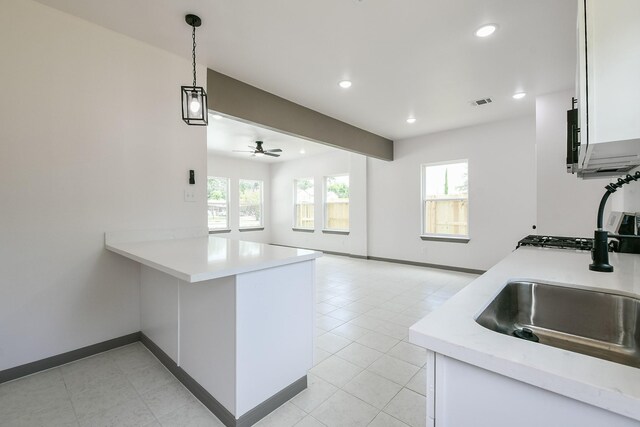 8306 E Tidwell Rd, Houston, TX 77028 - kitchen with light countertops, a peninsula, recessed lighting, white cabinets, and decorative light fixtures