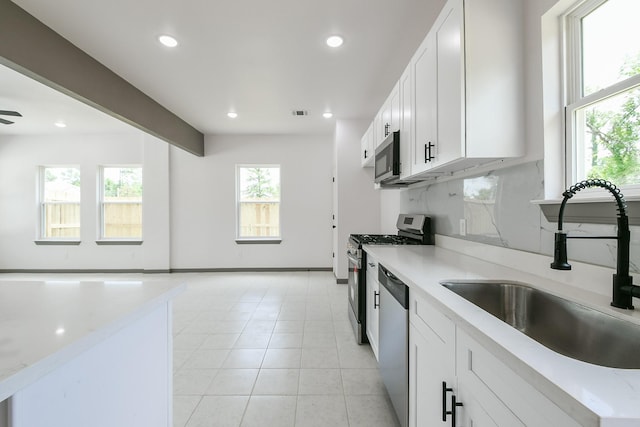 8306 E Tidwell Rd, Houston, TX 77028 - kitchen with appliances with stainless steel finishes, recessed lighting, white cabinetry, light tile patterned flooring, and light stone countertops