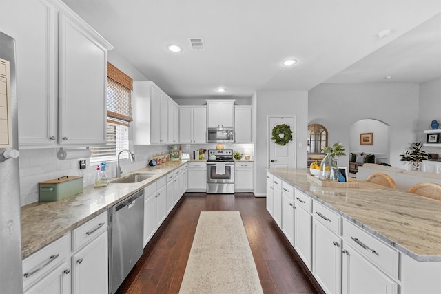 22402 Threefold Ridge Dr, Hockley, TX 77447 - kitchen featuring stainless steel appliances, light stone counters, a spacious island, white cabinetry, and decorative backsplash