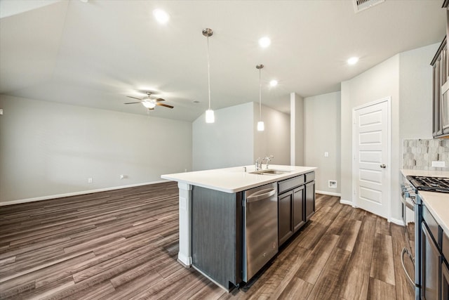 7222 Melrose Ln, Rosharon, TX 77583 - kitchen featuring appliances with stainless steel finishes, dark wood-style floors, a ceiling fan, backsplash, and a center island with sink